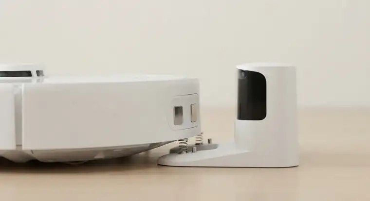 Robot sprzątający podłączony do stacji dokującej w domu, czekający w trybie czuwania na kolejne zaplanowane sprzątanie